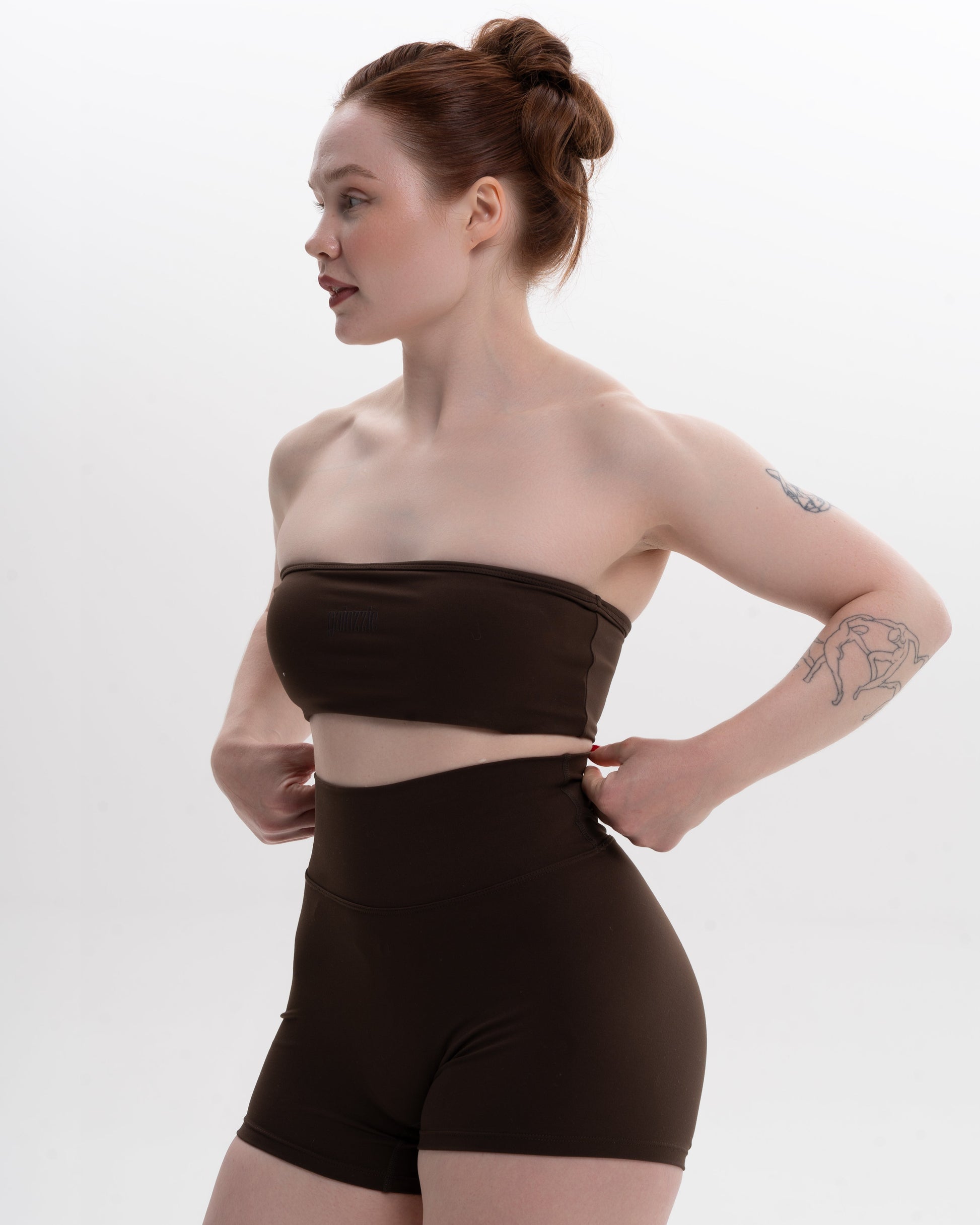 Woman wearing a brown strapless top and high-waisted shorts on a white background